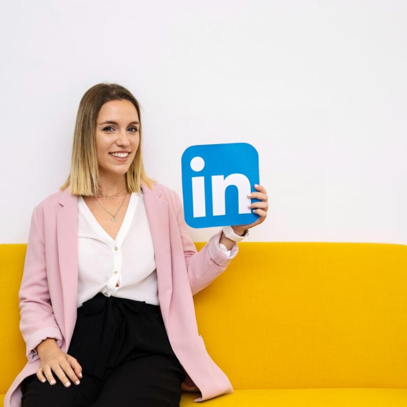 attractive-young-woman-sitting-sofa-holding-linkedin-icon.jpg
